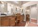 Bathroom with multiple sinks, wood cabinets, and hardwood floors at 14207 W Kiowa Trl, Surprise, AZ 85374