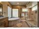 Elegant bathroom featuring a soaking tub, glass block window, and glass enclosed shower at 1423 E Breezy Ct, Phoenix, AZ 85086