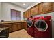 Laundry room featuring a sink, wooden cabinets, granite countertops, and red front load washer and dryer at 1423 E Breezy Ct, Phoenix, AZ 85086