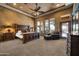 Luxurious main bedroom featuring a tray ceiling, decorative ceiling fan, sitting area and abundant natural light at 1423 E Breezy Ct, Phoenix, AZ 85086