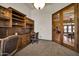 Cozy office featuring custom wood built-ins with desk space, shelving, and view to another interior living space at 1423 E Breezy Ct, Phoenix, AZ 85086