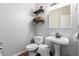 Compact bathroom featuring a pedestal sink, toilet, and two floating shelves for storage at 15808 N 164Th Ln, Surprise, AZ 85388