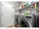 Bright laundry room with a modern washer and dryer, shelving, and wood-look flooring near a white door at 15808 N 164Th Ln, Surprise, AZ 85388