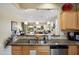 Open kitchen with granite counters, breakfast bar, stainless steel dishwasher, and view to living room at 21573 N 261St Ave, Buckeye, AZ 85396