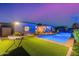 Backyard with a hammock, artificial grass, and a sparkling pool, offering a relaxing outdoor experience at 3125 W Desert Ln, Laveen, AZ 85339
