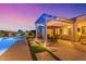 Backyard with a pool, covered patio, outdoor dining, and lush landscaping at dusk at 3125 W Desert Ln, Laveen, AZ 85339