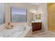Bathroom featuring a garden tub with tile surround, double sinks and natural light at 3125 W Desert Ln, Laveen, AZ 85339