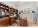 This home office features wood bookshelves, a desk and chair, plus a wall decorated with framed accolades at 3125 W Desert Ln, Laveen, AZ 85339