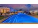 Long, modern swimming pool with artificial grass, lighting, and waterfall feature at 3125 W Desert Ln, Laveen, AZ 85339