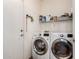 Bright laundry room featuring modern white washer and dryer units with open storage shelves at 318 E Taylor Trl, San Tan Valley, AZ 85143