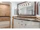 Bathroom with a dual sink vanity with granite countertop, a large mirror, and tiled shower and walls at 3413 E Equestrian Trl, Phoenix, AZ 85044