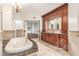 A primary bathroom featuring a soaking tub and a wooden vanity with marble countertop, complemented by neutral tiling at 3413 E Equestrian Trl, Phoenix, AZ 85044