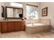 Bright bathroom includes a large soaking tub and a vanity with a large mirror at 42145 N Fairgreen Ct, Anthem, AZ 85086
