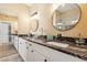 Double vanity bathroom featuring dark granite countertops and framed circular mirrors at 4353 E Desert Wind Dr, Phoenix, AZ 85044