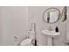 Bright half-bathroom with pedestal sink, toilet, and modern round mirror at 4803 S Ferric --, Mesa, AZ 85212