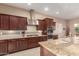 Updated kitchen with stainless appliances, granite countertops, mosaic backsplash, island with sink, and dark wood cabinetry at 4946 N 210Th Ave, Buckeye, AZ 85396