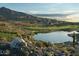 Stunning view of a peaceful pond along the golf course, surrounded by desert landscape and distant mountains at 4946 N 210Th Ave, Buckeye, AZ 85396