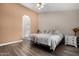 Cozy main bedroom featuring wood-look flooring, ceiling fan, ensuite bath, and large window at 6416 S 19Th Pl, Phoenix, AZ 85042