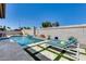 Sparkling pool featuring travertine tile and grassy accents, lounge chairs, and a custom waterfall feature at 8712 W Sequoia Dr, Peoria, AZ 85382