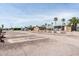 Mobile home community with gravel lots, palm trees, and open sky in a sunny landscape at 9333 E University Dr # 194, Mesa, AZ 85207