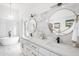 Modern bathroom featuring double sinks, marble accents, round mirrors, and a luxurious soaking tub at 10248 E San Salvador Dr, Scottsdale, AZ 85258