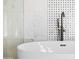 Closeup of a luxurious bathtub with a sleek black faucet and stylish white and black tile accents at 10248 E San Salvador Dr, Scottsdale, AZ 85258