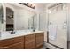 Well-lit bathroom with double sinks, a large mirror, and glass-enclosed shower at 11591 W Jefferson St, Avondale, AZ 85323