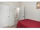Cozy bedroom features a red bedspread, white walls, and a doorway leading to other parts of the house at 11591 W Jefferson St, Avondale, AZ 85323