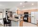 Cozy kitchen featuring a breakfast bar, light wood cabinets, black appliances and tile flooring at 11591 W Jefferson St, Avondale, AZ 85323
