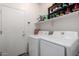 Laundry room with a white washer and dryer, overhead shelving, and a storage closet at 11591 W Jefferson St, Avondale, AZ 85323