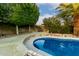 A pool with landscaping in the backyard with privacy wall and large tree at 14228 W Weldon Ave, Goodyear, AZ 85395