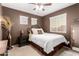 A bedroom with a large bed, multiple windows and a decorative mirror at 14228 W Weldon Ave, Goodyear, AZ 85395