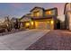 Well-lit home featuring an attached garage and a landscaped front yard at dusk at 14228 W Weldon Ave, Goodyear, AZ 85395