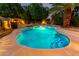 Sparkling pool with inviting lighting surrounded by lush landscaping and rock features at 14228 W Weldon Ave, Goodyear, AZ 85395