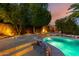 Inviting pool features landscape lighting, surrounded by lush greenery and unique accents at 14228 W Weldon Ave, Goodyear, AZ 85395