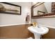 Charming powder room with a pedestal sink, decorative mirror, and wainscoting detail at 14228 W Weldon Ave, Goodyear, AZ 85395