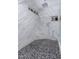 Modern walk-in shower with river rock floor, marble-style tiles, and built-in shelving at 1907 E Huber St, Mesa, AZ 85203