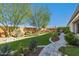 Expansive backyard featuring lush artificial turf, mature trees, and a beautifully paved walkway and seating area at 19215 N 259Th Ave, Buckeye, AZ 85396