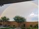View of a rainbow arching over the backyard with desert landscaping at 19215 N 259Th Ave, Buckeye, AZ 85396