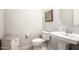 A clean powder room featuring a pedestal sink, toilet, and neutral decor at 19215 N 259Th Ave, Buckeye, AZ 85396