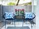 Relaxing patio area with two chairs, blue pillows, colorful flowering plants, and privacy wall at 1961 N Hartford St # 1087, Chandler, AZ 85225
