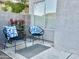 Cozy patio features two chairs with blue pillows, flowering plants, and exterior window at 1961 N Hartford St # 1087, Chandler, AZ 85225