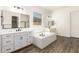 Bright bathroom boasts dual vanities, large tub, and wood look tile flooring at 20255 W Monterey Way, Buckeye, AZ 85396