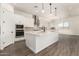 A modern kitchen features a large center island, stainless steel appliances, and plenty of white cabinetry at 20255 W Monterey Way, Buckeye, AZ 85396