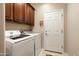 Functional laundry room with modern appliances, storage cabinets, and door at 20523 N 267Th Ln, Buckeye, AZ 85396