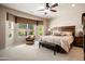 Serene main bedroom featuring a bay window, ceiling fan, and a king-size bed with a bench at 20523 N 267Th Ln, Buckeye, AZ 85396
