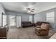 Cozy living room featuring neutral-colored walls, carpet, a ceiling fan, and comfortable brown leather seating at 30954 W Whitton Ave, Buckeye, AZ 85396