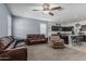Open-concept living room area with neutral-colored walls, carpet, a ceiling fan, and a kitchen in the background at 30954 W Whitton Ave, Buckeye, AZ 85396