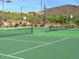 Community tennis court with well-maintained surface, nets, and lighting for evening play and lush greenery at 34710 N 27Th Ave, Phoenix, AZ 85086