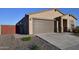 Tan single-Gathering home featuring a brown garage door, desert landscaping and walkway, and a partially fenced yard at 37049 N Lokai Dr, San Tan Valley, AZ 85140